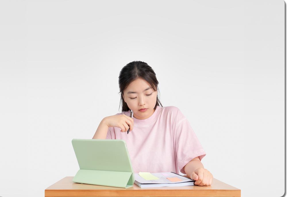 태블릿과 책을 살펴보는 학생
