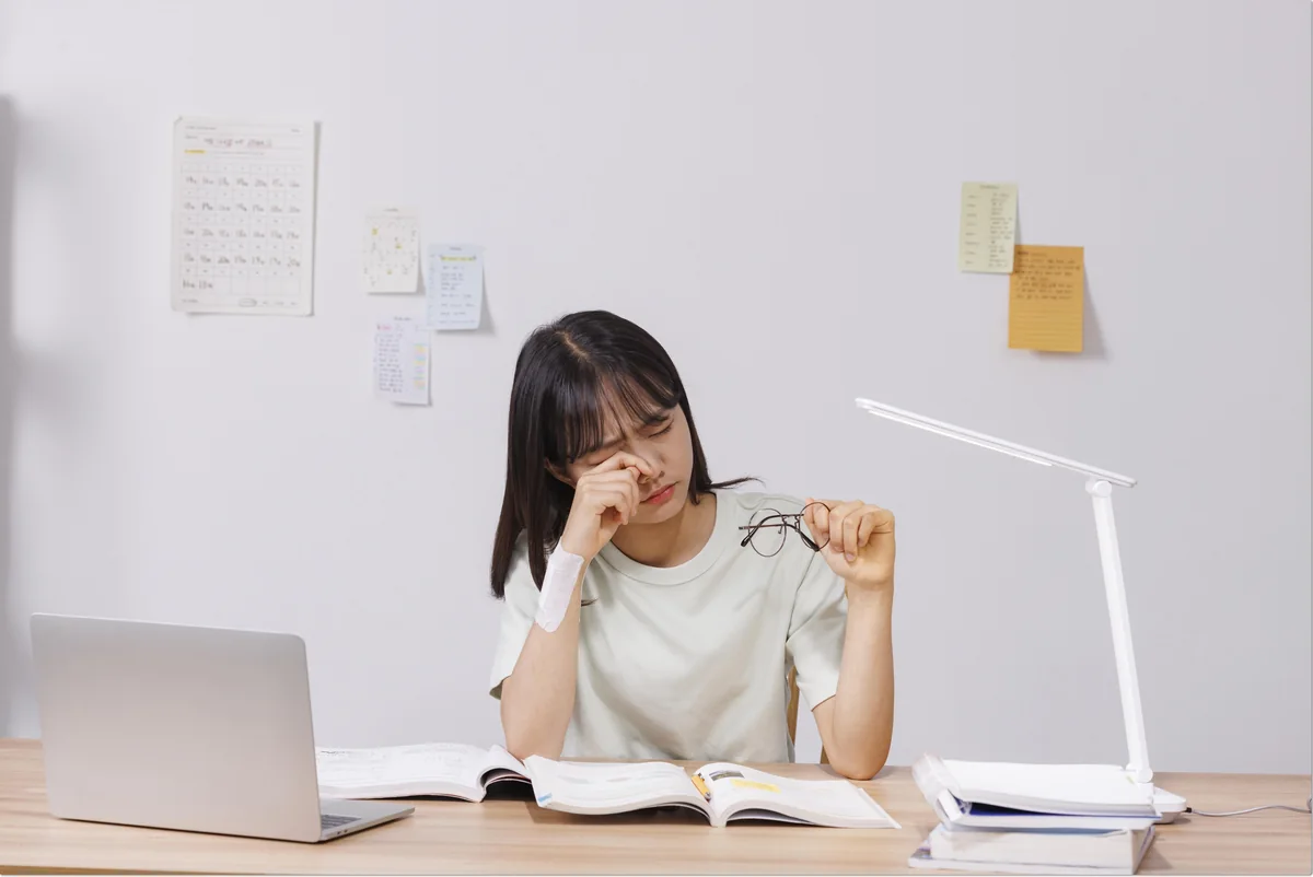 책과 노트북을 앞에 두고 생각하는 학생
