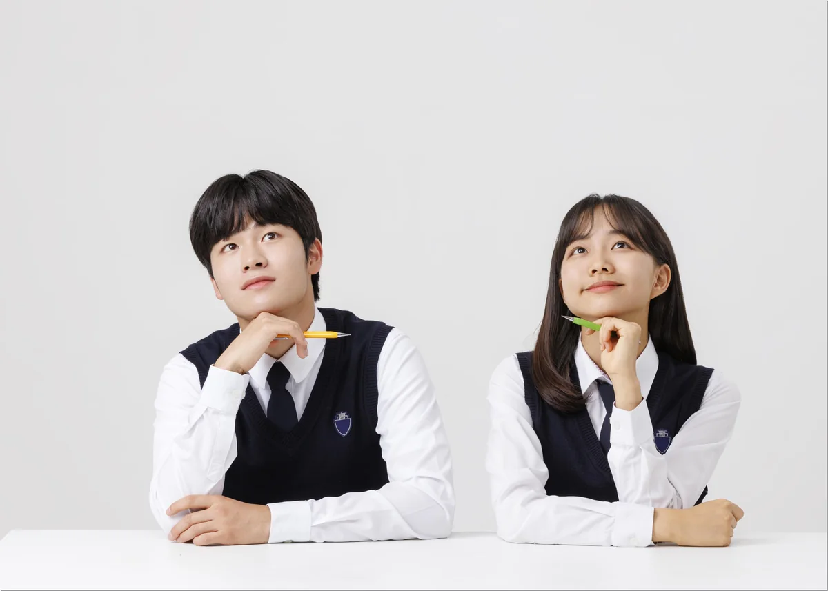 책을 앞에 두고 생각하는 두 학생