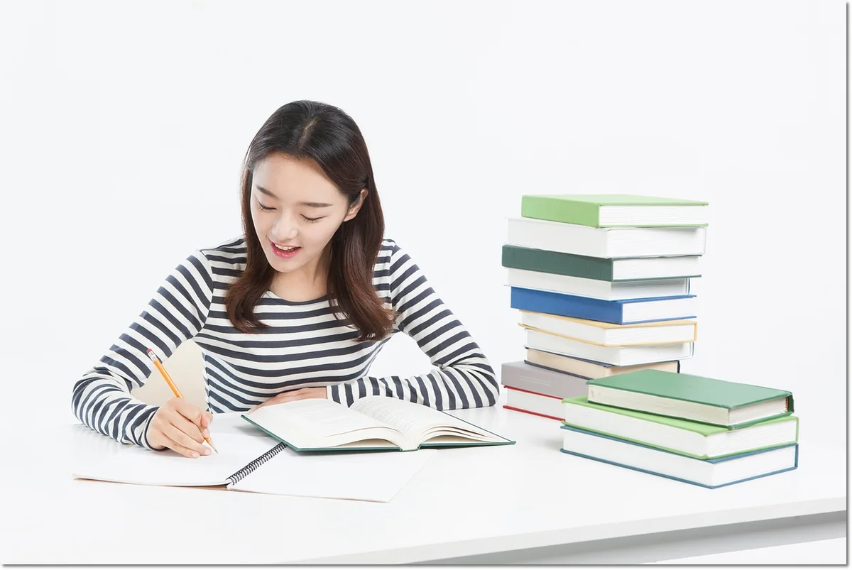 책이 쌓인 책상에서 내용을 읽는 학생