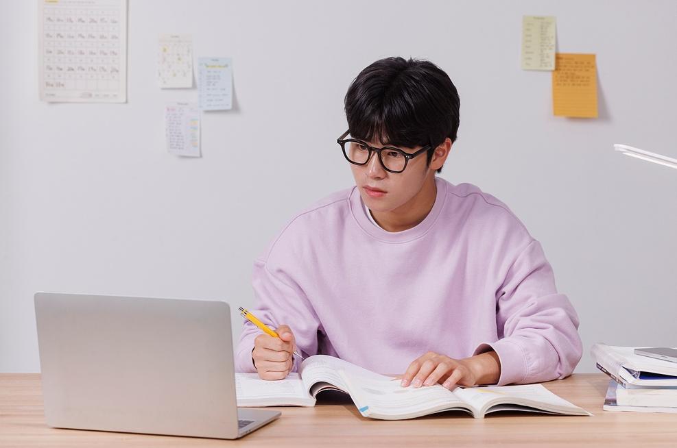 책과 노트북으로 공부하는 학생